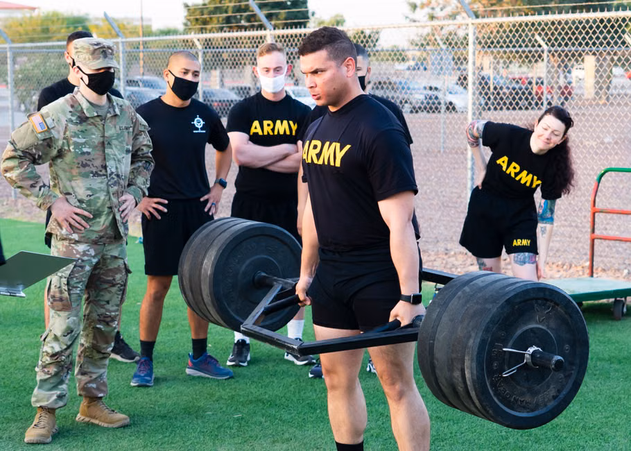 Army personnel participating in an outdoor weightlifting training session, showcasing teamwork and strength.